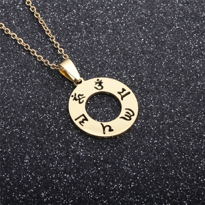 Macro detail of golden stainless steel round pendant with 3D engraved Buddhist symbols