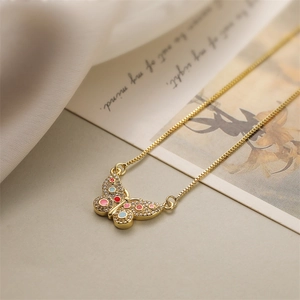 Macro view of gold butterfly pendant with colorful droplets and sparkling zircon inlay