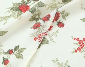 Close-up of floral print fabric with red roses and professional overlock stitching detail