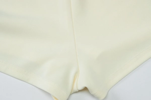 Détail des coutures doubles sur le tissu en maille blanc crème des shorts