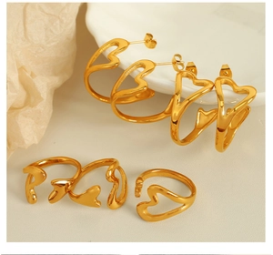 Polished gold hollow heart-shaped earrings and ring set on minimalist beige backdrop