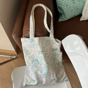 Detailed view of floral cotton tote bag texture with white shoulder straps on a chair