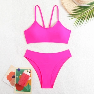 Neon pink bikini set with tank top and bottoms laid on white fur with beach accessories
