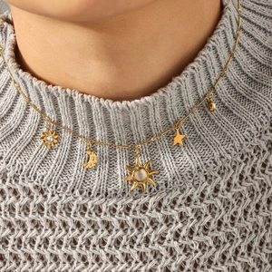 Collier en acier doré avec pendentifs lune étoile soleil sur pull gris