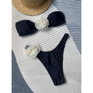 Two-piece black bikini set with 3D white fabric flowers on bandeau top and high-cut briefs