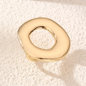 Close-up of polished gold-finish irregular ring with fluid oval design on stone texture