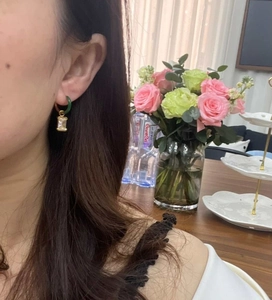 Close-up of model wearing gold earrings with dark green hoops and clear zircon stones