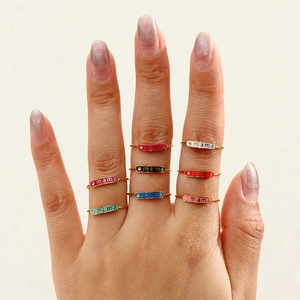 Detail showing stacked colorful mama rings in gold finish with vibrant enamel charms
