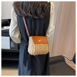 Detail of handmade straw crossbody bag with brown leather flap and golden twist lock