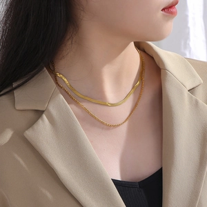 Close-up of golden double-layer necklace with flat snake chain and Figaro link style
