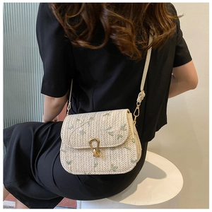 Détail du sac bandoulière en paille avec broderie florale et fermoir fer à cheval doré