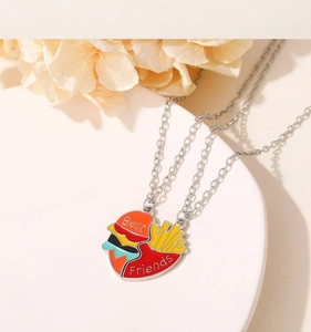 Macro detail of Best Friends necklaces with rainbow burger and fries charms on a white plate