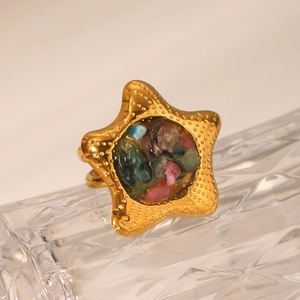 Macro view of gold starfish ring with colorful natural stone inlay on a glass prop