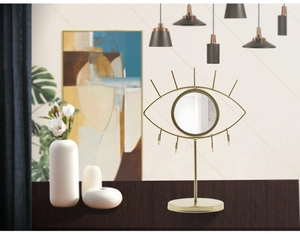Detailed view of eye-shaped gold jewelry organizer mirror with hooks on wood surface