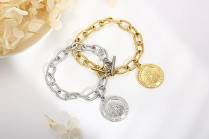 Close-up of gold and silver chain bracelets with Virgin Mary coin charms and T-bar clasps