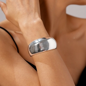 Detailed view of a wide polished silver geometric open cuff bracelet on a model's wrist