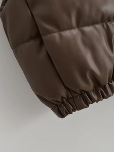 Detail of a brown leather padded vest showing the elastic hem and quilted stitching texture