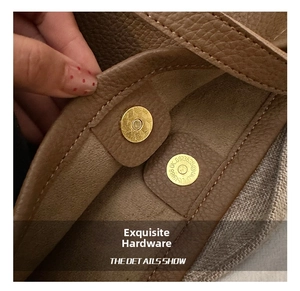 Detail of lychee pattern brown leather bag with golden magnetic clasp and gray lining