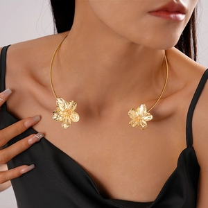 Detailansicht eines goldenen Metall-Chokers mit strukturierten Blumen auf Satin-Outfit