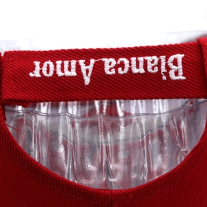 Detail of white Bianca Amor embroidery on red twill fabric of a thick baseball cap