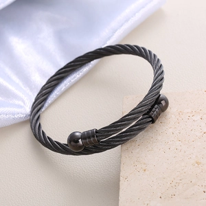 Modern twisted cable stainless steel bangle with spherical ends on natural stone
