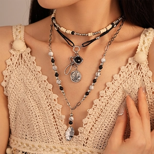 Detail of bohemian layered necklace with geometric pendants and black faux wood beads