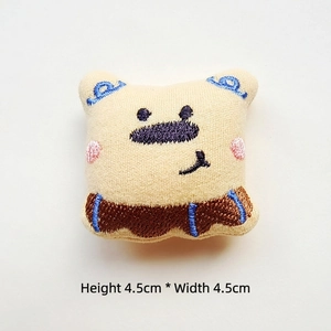 Detail view showing a 4.5cm cream plush bear brooch with colorful embroidery
