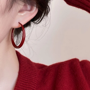 Close-up of model wearing cherry red hoop earrings paired with a matching knit sweater