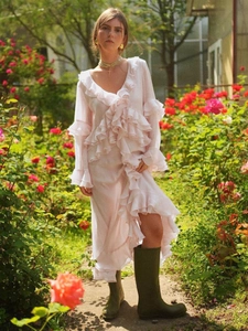Pink V-neck long dress with tiered ruffles and side slit in a garden setting