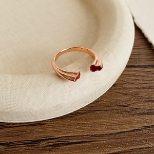 Détail d'une bague double gourde en or rose avec émail rouge sur un plateau chic