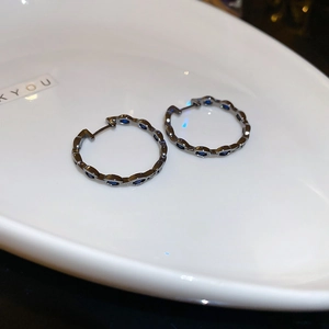 Macro view of geometric black metal hoop earrings with round blue zircon stones