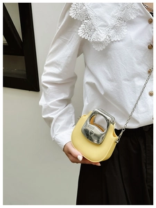 Close-up of mini yellow PU leather shoulder bag with silver handle and chain strap