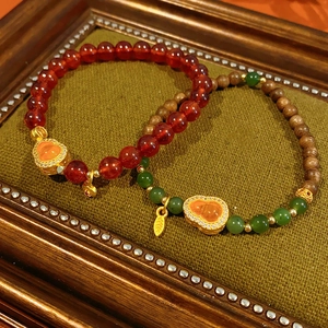 Close-up of vintage garnet and jade gourd bracelets on green velvet display base