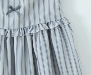 Detailed view of striped dress featuring grey satin bow and ruffled hem craftsmanship