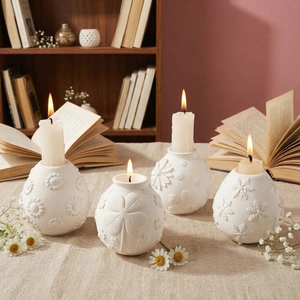 Set of four white ceramic spherical candle holders with embossed floral and clover designs