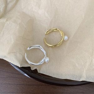 Detailed view of silver and gold pearl rings on textured beige paper background