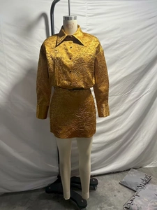 Detail van een gouden satijnen tweedelige set met shirt en minirok op een etalagepop