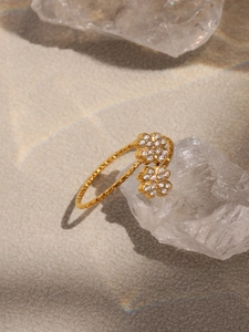 Détail macro d'une bague fleur à quatre feuilles dorée avec zircons sur cristal