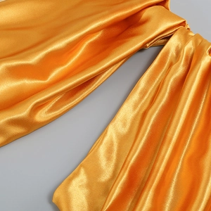 Gros plan sur un tissu satiné doré à la texture soyeuse et aux plis élégants