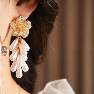 Gros plan de boucles d'oreilles fleur dorée avec zircon et pampilles de perles blanches