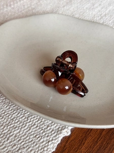 Vue détaillée d'une pince à cheveux en résine ambrée à billes sur une assiette en céramique