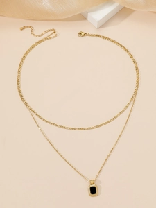 Detail of double-layer gold titanium necklace featuring a black rectangular pendant