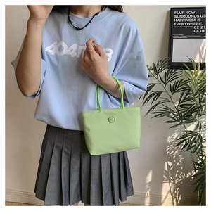 Gros plan sur le sac seau en nylon vert clair avec doubles anses et logo circulaire