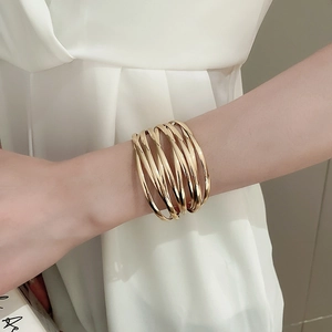 Detail of a minimalist multi-layer gold wrap cuff bracelet worn on a model's wrist