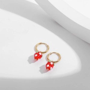 Detailed macro shot of red enamel strawberry heart earrings with golden metal hoops