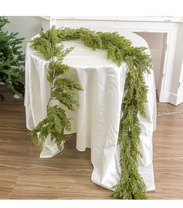 Detailed view of green faux cedar garland draped over a table for Christmas decoration