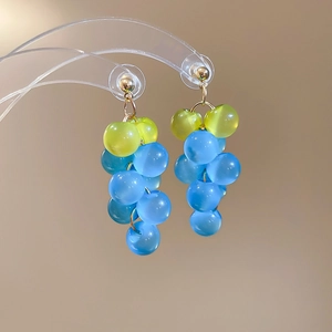 Detail shot of light green and sky blue resin grape cluster earrings on a stand