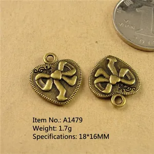 Macro view of vintage bronze heart pendant with bow relief and 18x16mm size scale