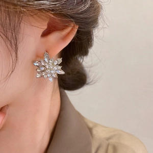 Close-up of a sparkling silver flower stud earring featuring brilliant crystal petals on model