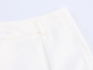 Détail de la taille blanc crème avec dentelle et perles brodées sur un pantalon chic